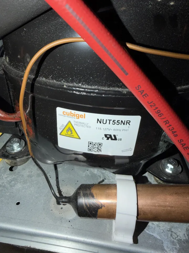 Refrigerator compressor connected to service equipment during sealed-system testing