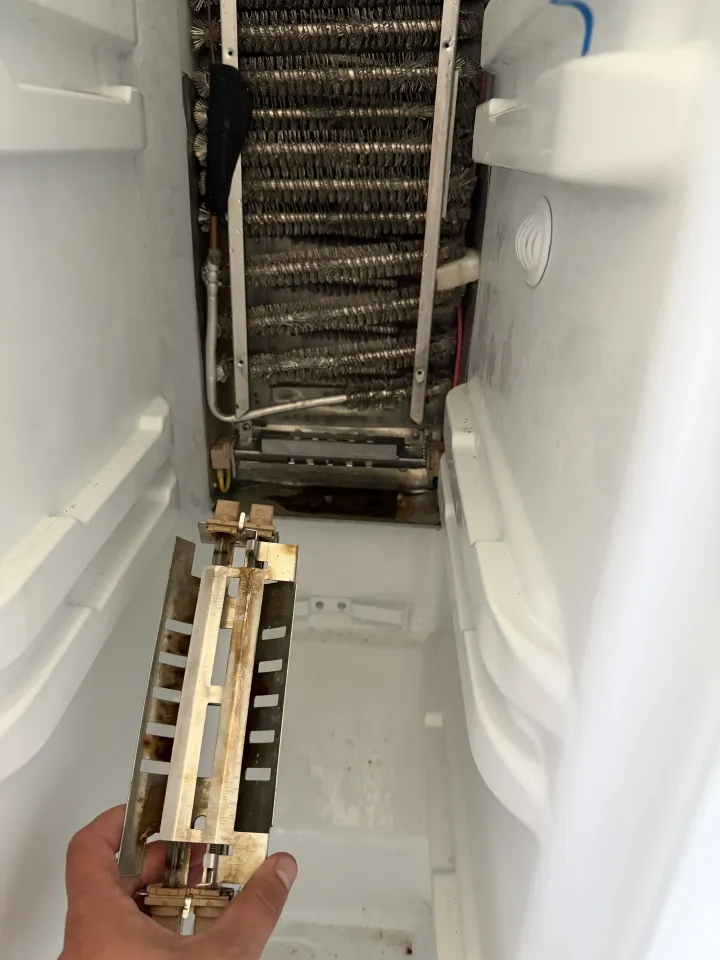 Refrigerator evaporator coil exposed after frost removal for component testing